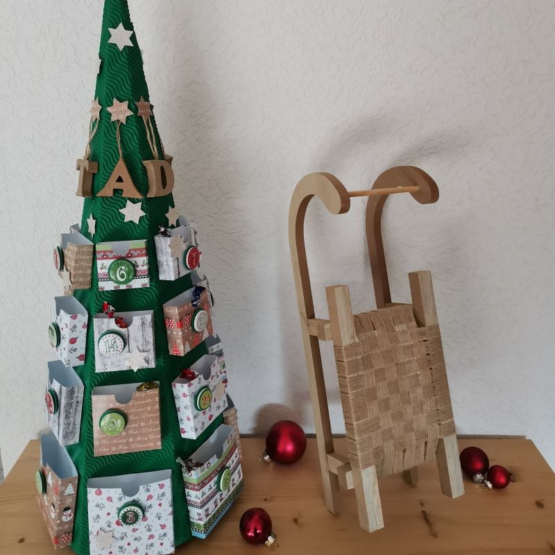 Stimmungsbild mit Tannenbaum-Adventskalender Schlitten und roten Weihnachtskugeln